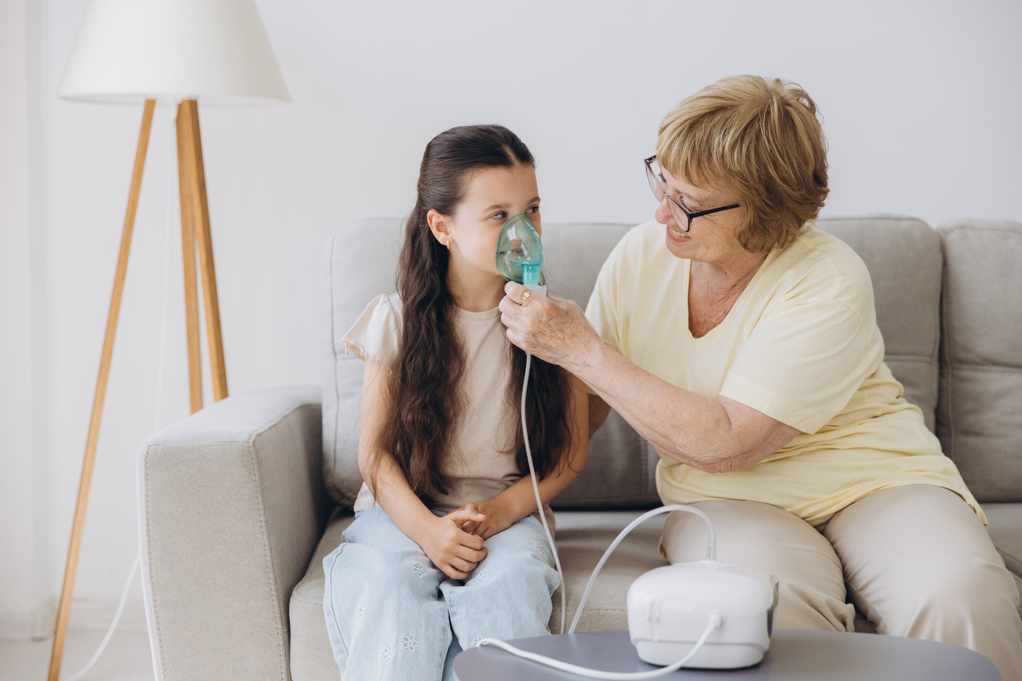 Little girl making inhalation with nebulizer with granny.